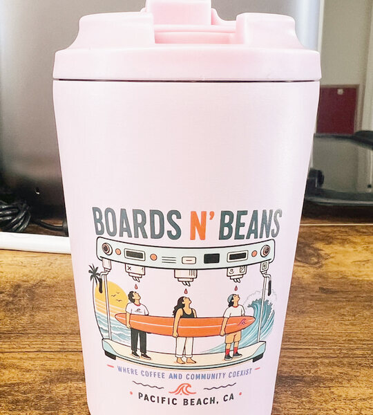 Close-up of a pink Boards n' Beans cup with a full-color printed surf illustration