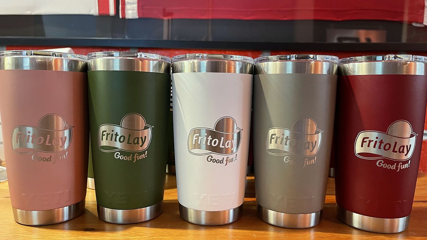 Row of five tumblers engraved with a company logo