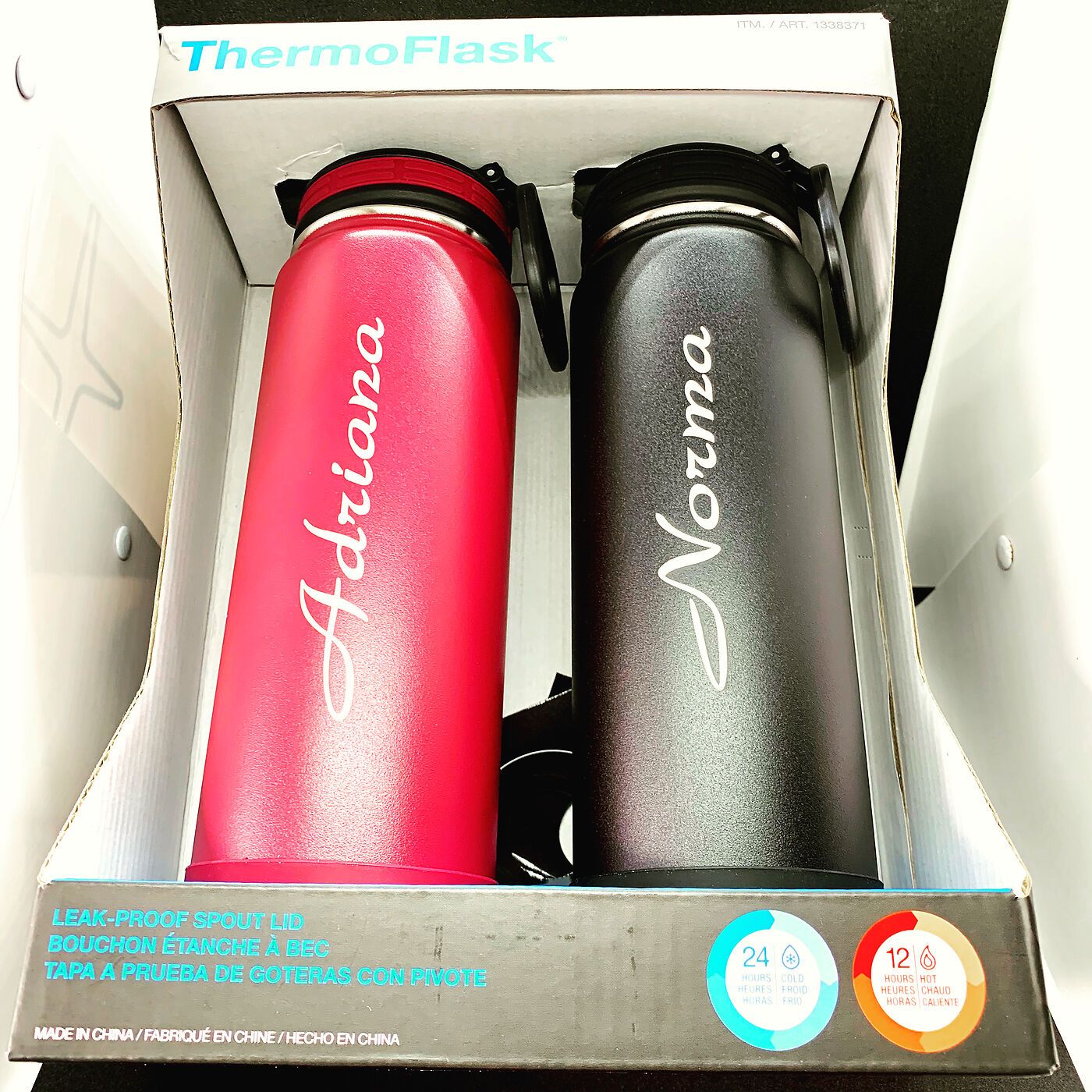 Red and black water bottles engraved with the names Adriana and Norma