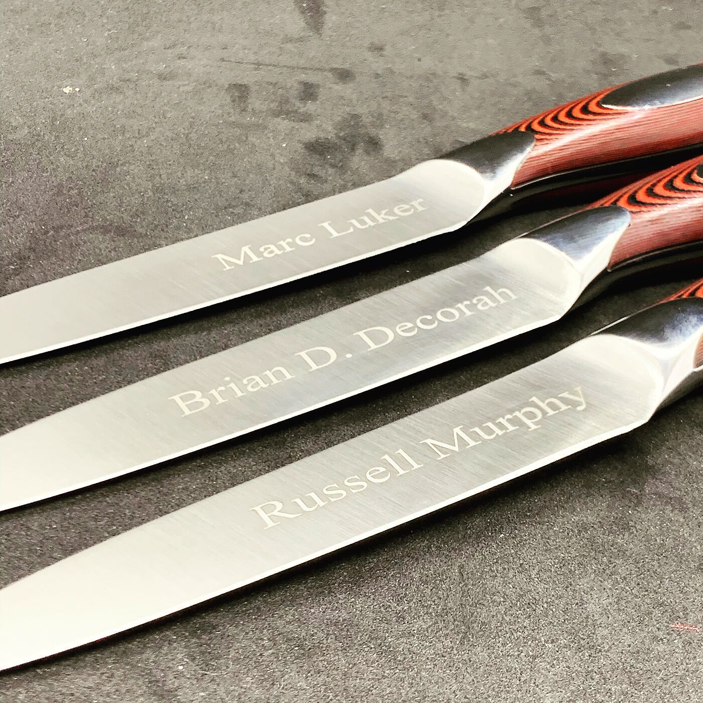 Three steak knives engraved with names on the blades